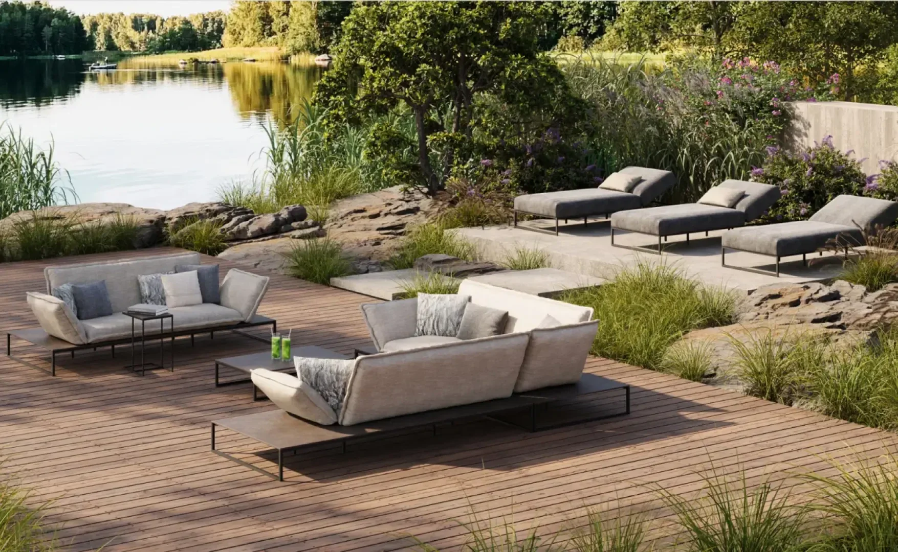 Moderner Lounge-Bereich im Freien mit gepolsterten Sofas und Sesseln auf einem Holzdeck mit Blick auf einen ruhigen See, umgeben von Felsen, hohem Gras, Bäumen und üppigem Grün.