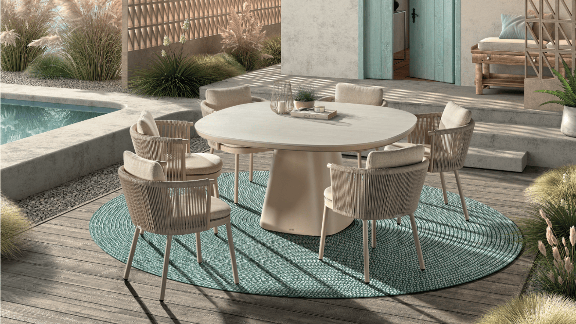 Ein moderner Essbereich im Freien besteht aus einem runden beigen Tisch mit sechs gepolsterten Stühlen auf einem runden türkisfarbenen Teppich, der auf einer Holzterrasse neben einem Pool steht und von dekorativen Pflanzen umgeben ist.
