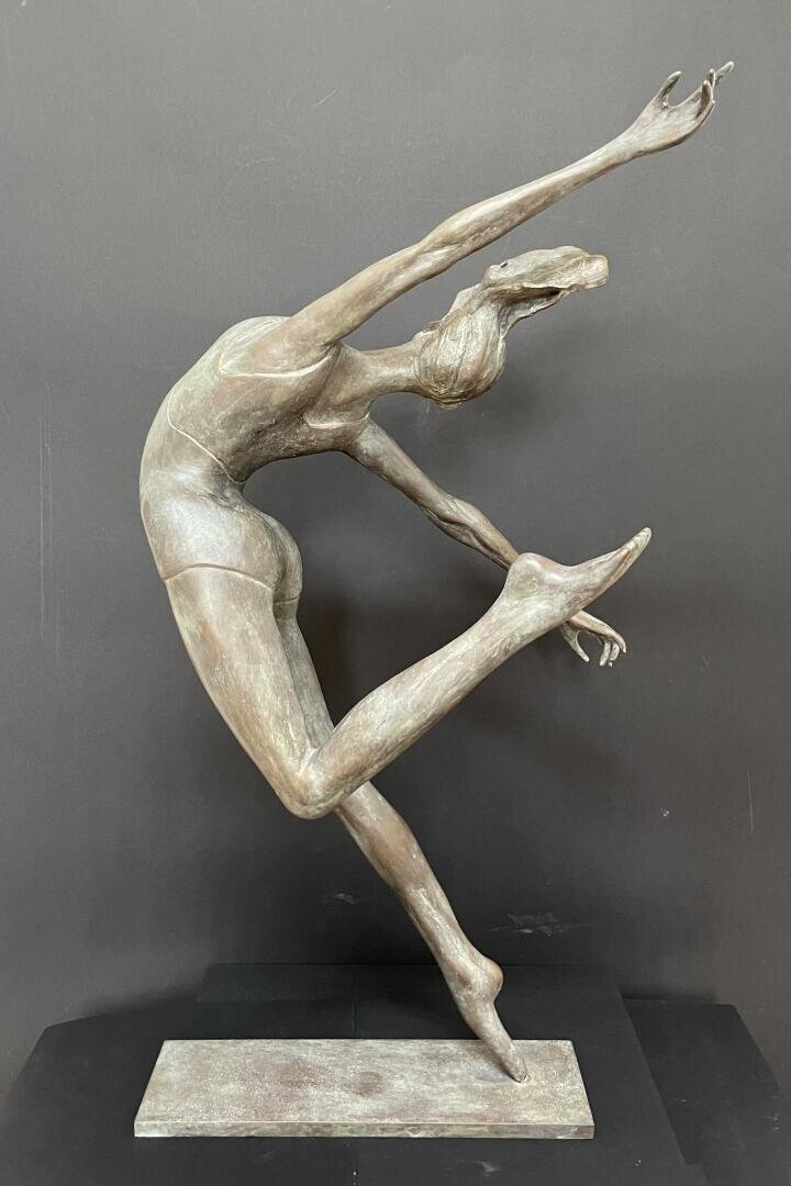 Bronzeskulptur einer anmutigen Tänzerin in geschwungener Haltung, die auf einem Bein balanciert und die Arme und das andere Bein elegant ausstreckt, vor einem dunklen Hintergrund.