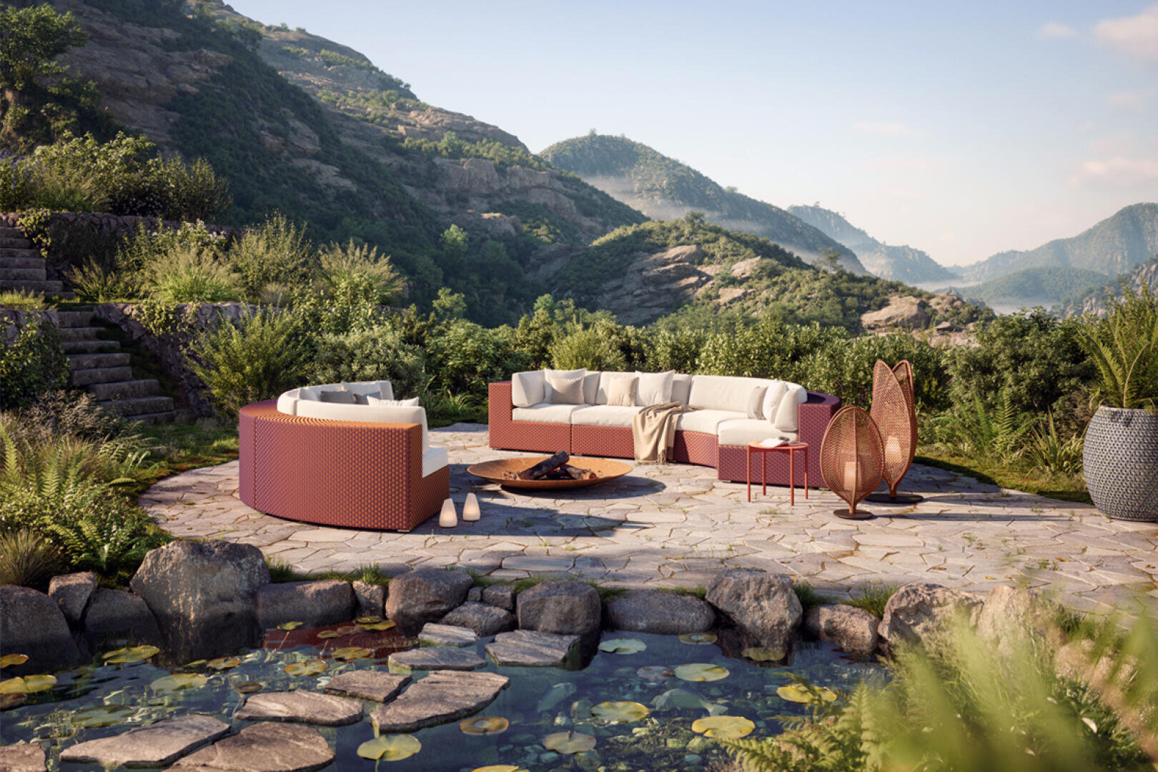 Geschwungene Sitzgelegenheiten mit Kissen umgeben eine Feuerstelle auf einer Steinterrasse, eingebettet in eine üppige, bergige Landschaft mit Grünpflanzen und einem Teich mit Seerosenblättern und Felsen im Vordergrund.