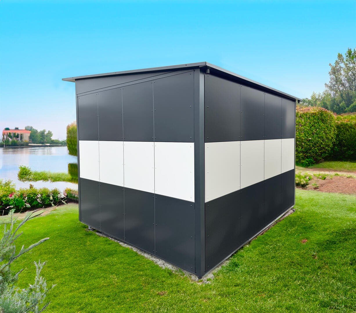 A modern, dark gray metal shed with a white horizontal stripe stands on a meadow near a lake, surrounded by bushes and trees under a clear blue sky.