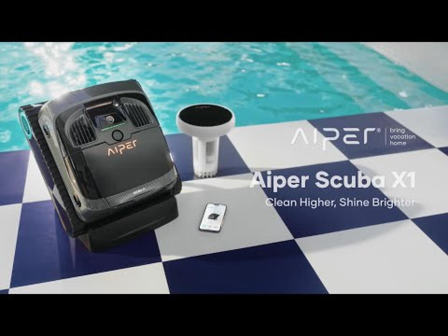 A robotic pool cleaner called Aiper Scuba X1 lies on a blue and white tiled poolside next to its charging station and a remote control, while a swimming pool and a brand slogan can be seen in the background.