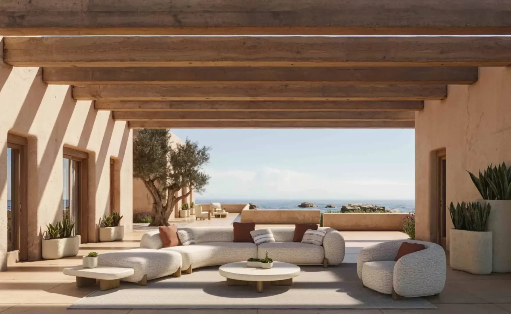 A modern outdoor living space with light-colored curved sofas and round tables under a wooden pergola, overlooking a patio and a scenic ocean view. Potted plants are placed around the seating area.