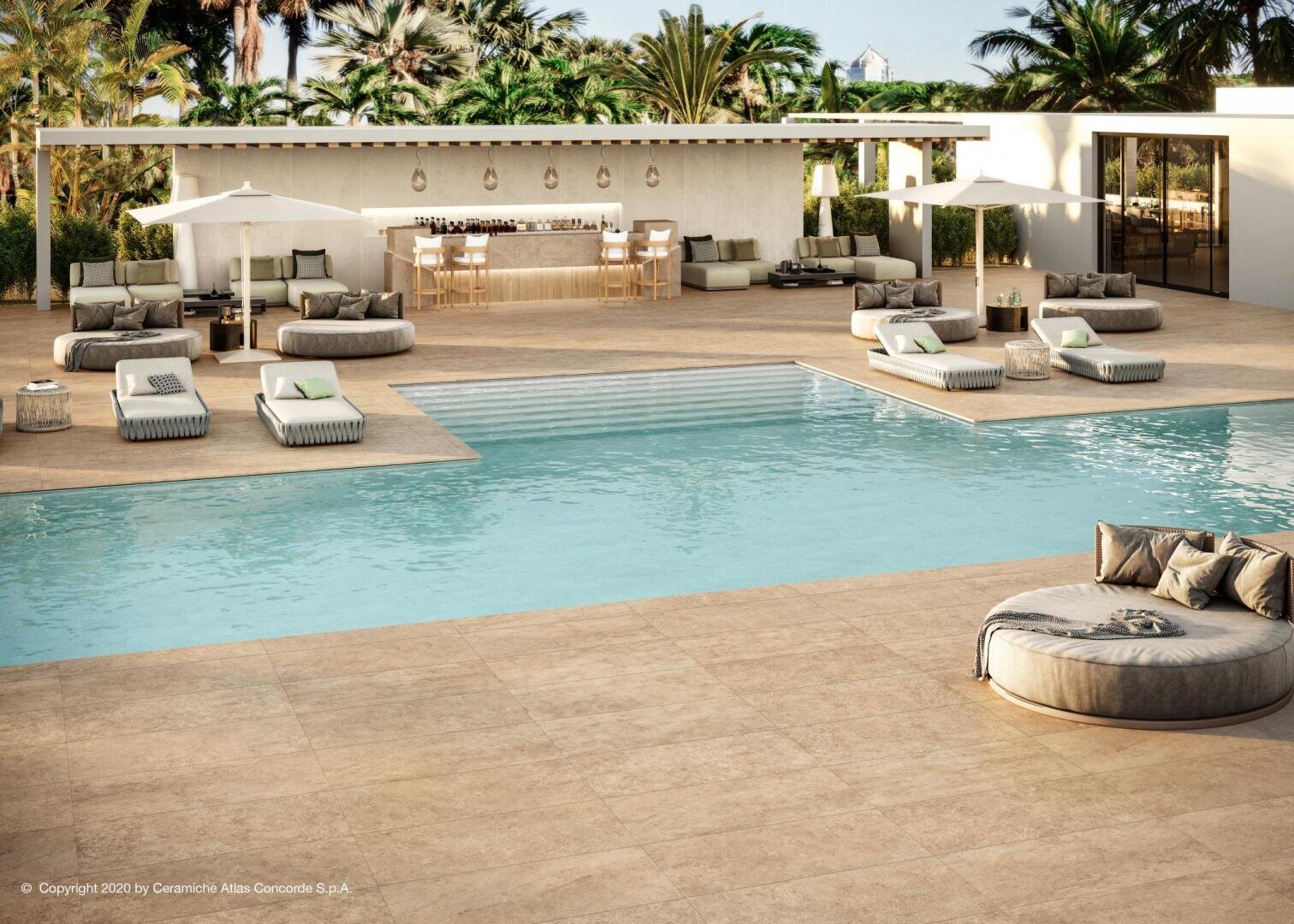 A luxurious outdoor pool area with modern lounge chairs, sofas, and umbrellas surrounding a clear blue swimming pool. In the background, there is a stylish bar and seating area, with palm trees and greenery around.
