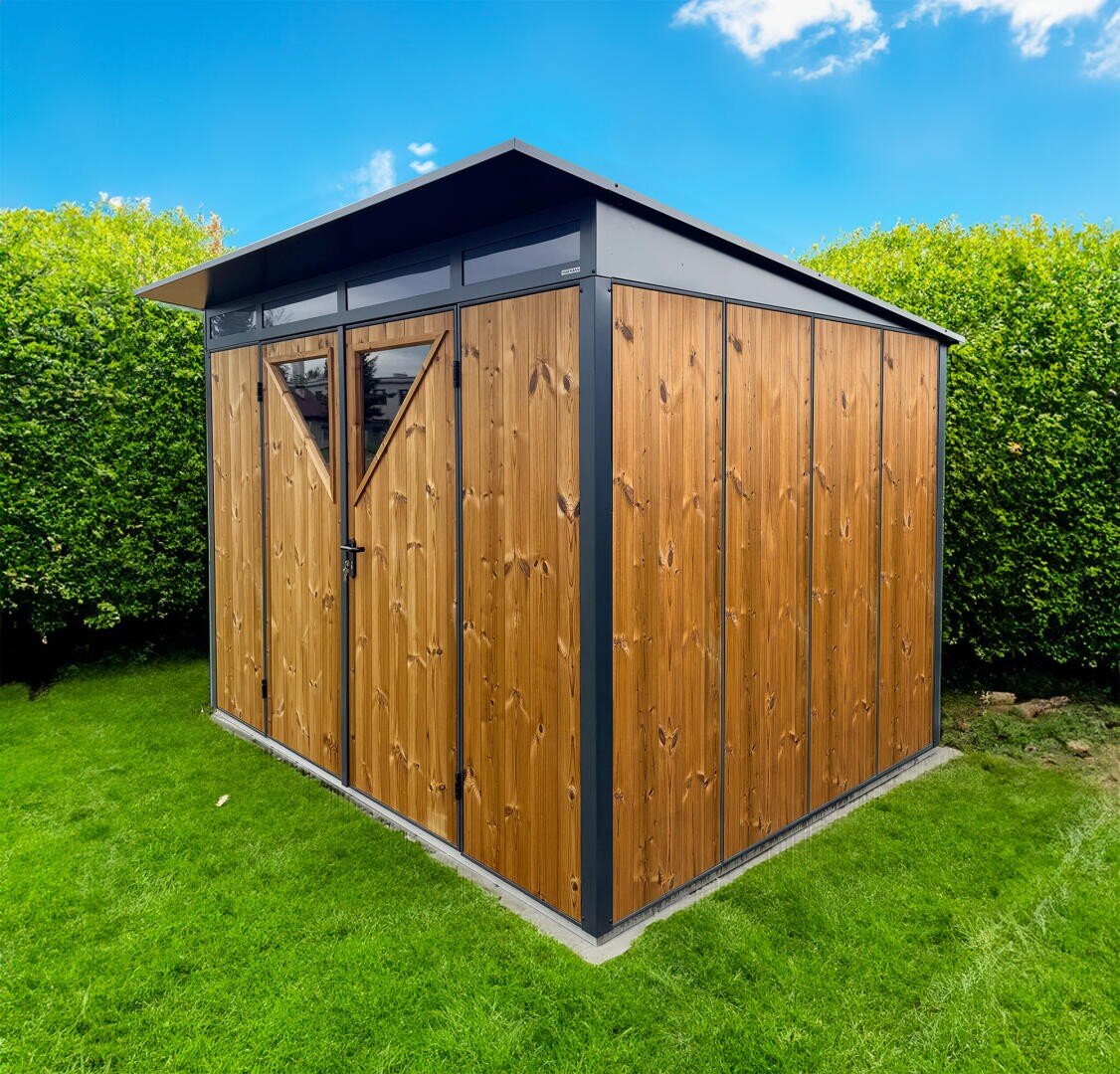 A modern garden house with wood-paneled walls and a pitched roof stands on a green meadow, surrounded by high, dense hedges, under a bright blue sky with a few clouds.
