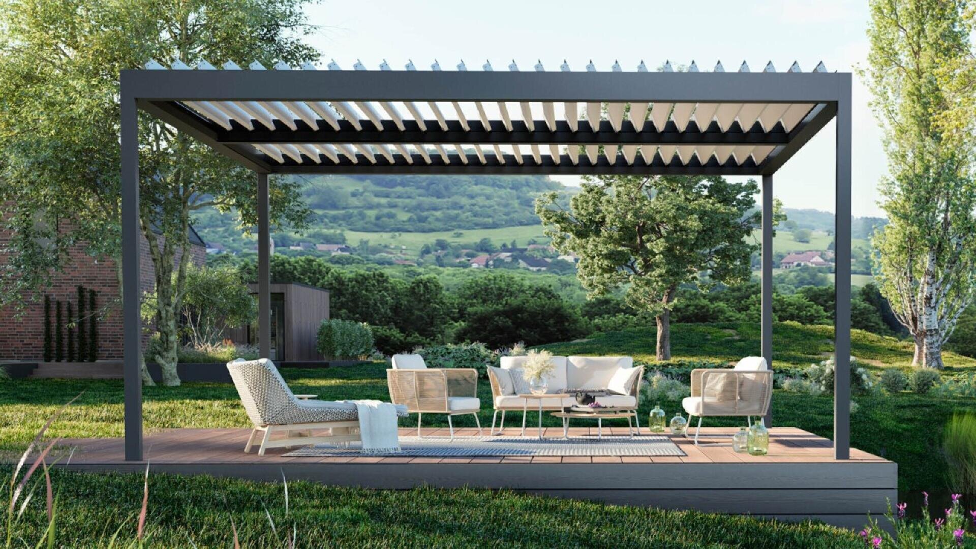 A modern outdoor pergola with white chairs and a table on a wooden deck, surrounded by lush greenery, trees, and distant hills under a partly cloudy sky.