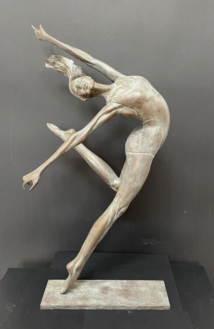 Bronzeskulptur einer anmutigen Balletttänzerin, die auf einem Fuß balanciert, die Arme und ein Bein elegant ausstreckt, den Kopf nach hinten neigt und das Haar fließen lässt, vor einem schlichten dunklen Hintergrund.