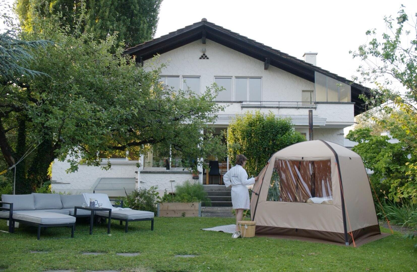 Eine Frau steht in einem Hof neben einem Zelt.