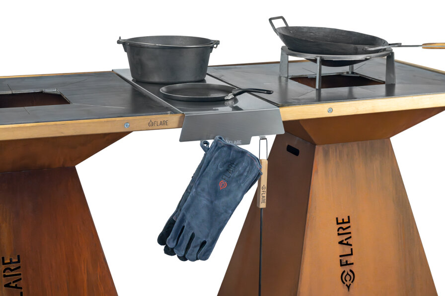 A metal outdoor grill station with a grill surface, pots and pans on it, a pair of heat-resistant gloves hanging on a hook and the FLARE brand on the sides.