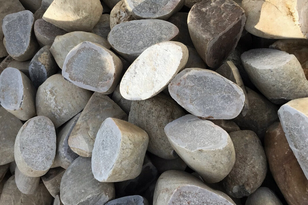 Ein Haufen großer, grob behauener grauer und beiger Steine, die dicht nebeneinander gestapelt sind und im natürlichen Sonnenlicht verschiedene Formen und Texturen aufweisen.