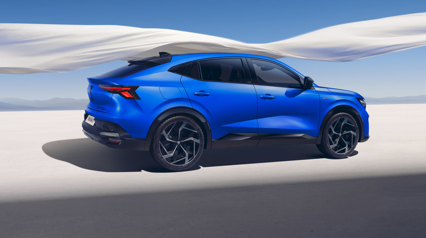 Ein schnittiger, leuchtend blauer Geländewagen mit schwarzen Akzenten ist in einer modernen, minimalistischen Landschaft unter einem klaren blauen Himmel geparkt, über dem ein fließender weißer Stoff hängt.