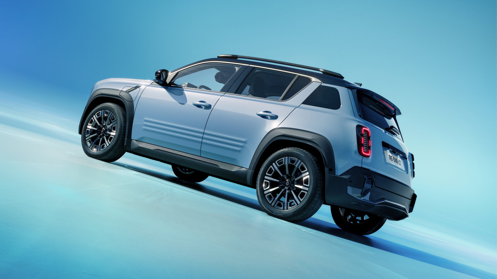 Ein hellblauer kompakter Geländewagen mit schwarzer Zierleiste und Dachreling ist auf einer glänzenden, blauen Farbverlaufsfläche geparkt, fotografiert aus der hinteren Seitenansicht vor blauem Hintergrund.