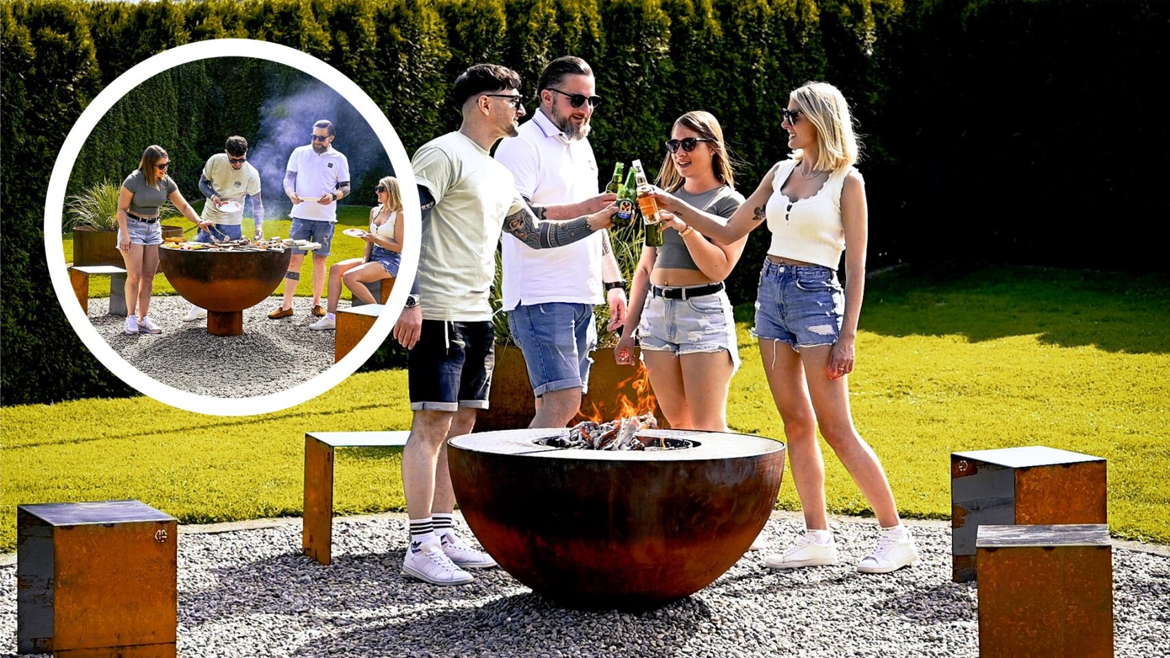 Four people are standing around a round outdoor fireplace, toasting drinks in a garden. In the background, two people can be seen grilling food at the same fire pit while others watch nearby. It is sunny and everyone looks relaxed and happy.