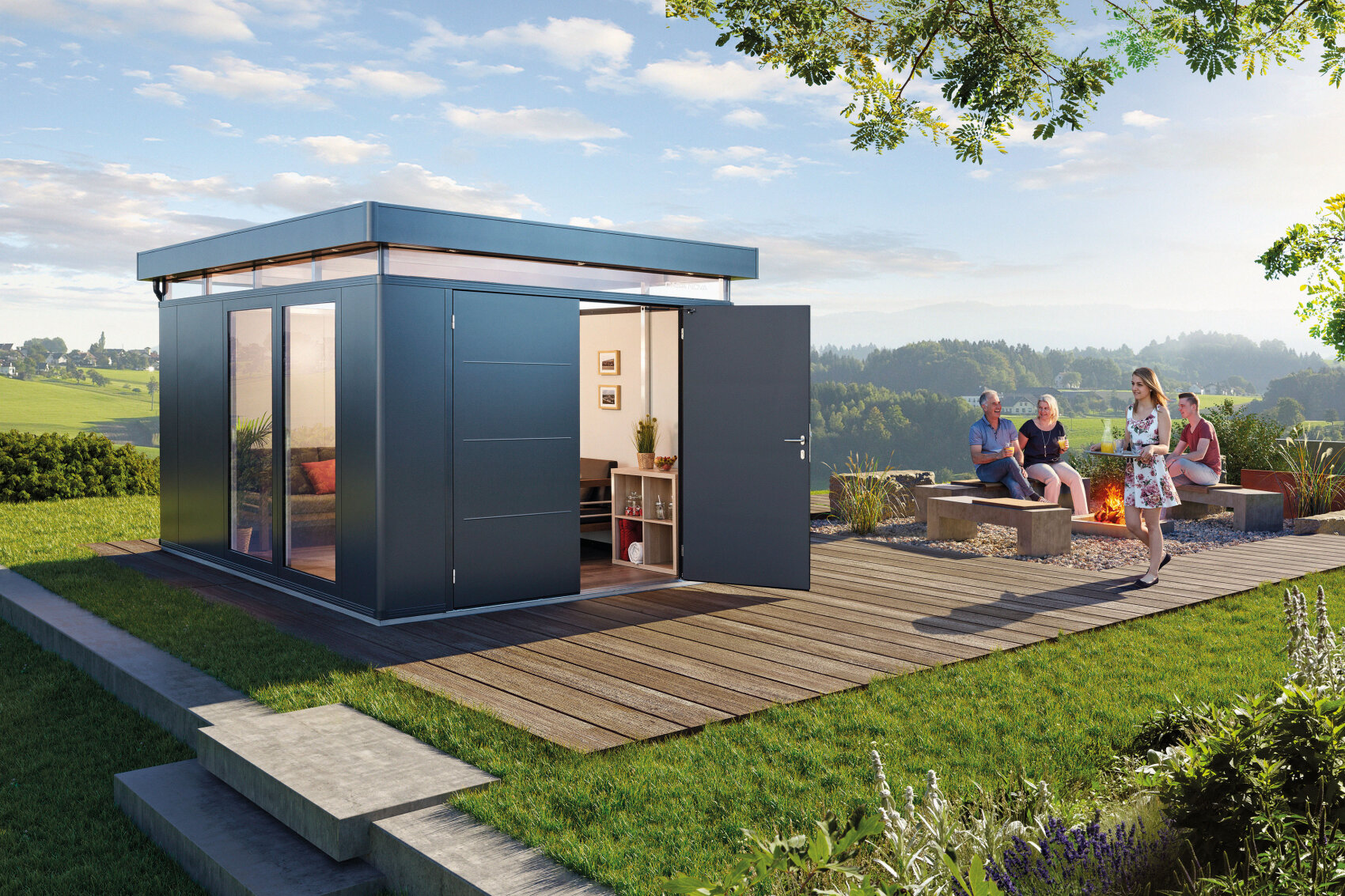 A modern garden room with open doors sits on a wooden deck. Nearby, four people relax around a fire pit, surrounded by greenery and open fields under a blue sky with clouds.